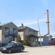 Des maisons du quartier Notre-Dame à Rouyn-Noranda, une cheminée de la Fonderie Horne en arrière-plan.