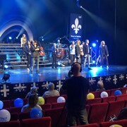 Des membres de Québec Issime sur scène devant un public distancié. 