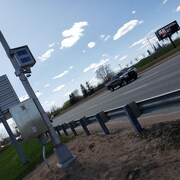 Un appareil radar photo fixe le long d'une autoroute où circule une camionette 