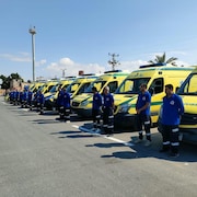 Des ambulanciers attendent près d'une rangée d'ambulance.