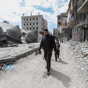 Un homme et un enfant palestiniens passent devant une mosquée réduite à l’état de ruine.