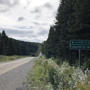 Chemin de terre avec une pancarte montrant des indications routières.