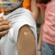 Un enfant lève sa manche pour montrer un pansement après avoir reçu un vaccin contre la COVID-19 à Vancouver le lundi 29 novembre 2021.