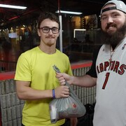 Un fan de basketball abordant son gilet des Raptors pose fièrement avec son don en denrée non périssable.
