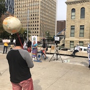 Des manifestants, notamment un homme de dos tenant un manche avec au bout, un globe. 