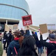 Des manifestants tiennent des pancartes devant un immeuble à Winnipeg le 1er octobre 2022. 
