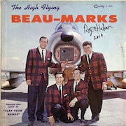 Quatre hommes posent devant un avion sur une couverture d'album de musique. 