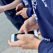 Des mains d'adolescents qui pianotent sur leur téléphone cellulaire.