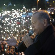 Recep Tayyip Erdogan, de profil, prononce un discours au micro devant une foule.
