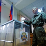 Un soldat de la république populaire autoproclamée de Lougansk glisse son bulletin de vote dans l'urne. 