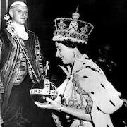 La reine Elisabeth II, souriante, marchant lors de son couronnement avec le sceptre et l'orbe.