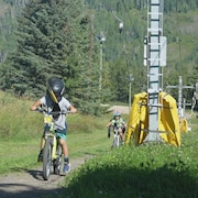 Une personne sur un vélo est tirée par un remonte-pente pour se rendre jusqu'au haut du sentier. (août 2023)