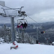 Des skieurs sur une remontée mécanique du Mont-Sainte-Anne, en hiver.