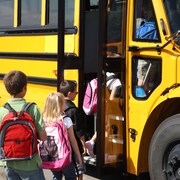 Des élèves montent à bord d'un autobus scolaire.

