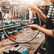 Une femme répare une roue de vélo dans un atelier.