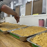 Un service de traiteur est en train de préparer du macaroni au fromage pour les athlètes.