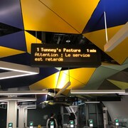 Sur le panneau, on peut lire : « Attention : Le service est retardé ».