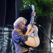 Richard Séguin lève sa guitare devant le micro placé devant lui.