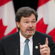 Richard Wagner, devant des drapeaux canadiens, tient une conférence de presse.