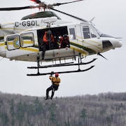 Une personne descend en rappel d'un hélicoptère de la Sûreté du Québec.