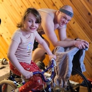 Robert Kirschman sur son vélo d'appartement à côté de sa fille Aubrey. 