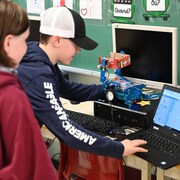 Des élèves dans une classe font de la programmation sur un ordinateur. 