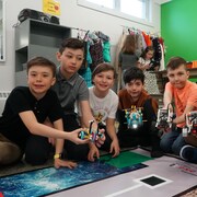 Sept garçons sur un tapis avec un robot dans les mains.