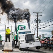 Deux camions au départ d'une course produisent de la fumée.