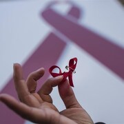 Une femme tient dans ses mains un ruban rouge, signe de la lutte contre le VIH et le sida.