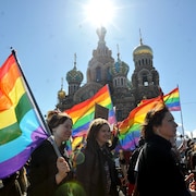 Des militants pour les droits L G B T Q + marchent avec des drapeaux arc-en-ciel à Saint-Pétersbourg.
