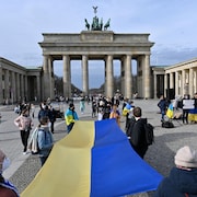 Des manifestants tiennent un immense drapeau de l'Ukraine sur une place de Berlin.