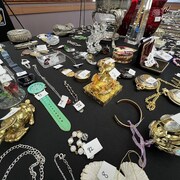 Une table avec une nappe noire o&ugrave; des bijoux, des bibelots, des urnes et divers objets de valeur sont dispos&eacute;s et num&eacute;rot&eacute;s.