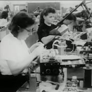 Femmes attablées, travaillant manuellement sur des produits électroniques.