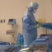Une personne habillée d'une combinaison sanitaire s'affaire dans une salle d'opération.