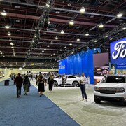 Des visiteurs marchent devant des véhicules Ford au Salon international de l'auto.