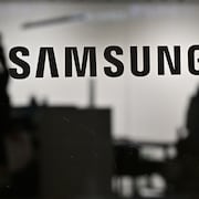 Le logo de Samsung est affiché avec des ombres de personnes en arrière-plan.