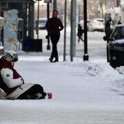 Une personne sans abri assise dehors en hiver.