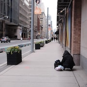 Un sans-abri assis sur le trottoir.