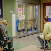 Une infirmière et une bénévole de Services de santé Alberta assises près d'une salle de soins intensifs.