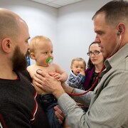 Un homme examine deux enfants avec un stéthoscope.