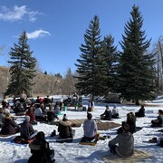 Des gens assis en cercle sur la neige.