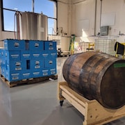 Intérieur d'une distillerie, avec gros baril de bois et caisses empilées. 