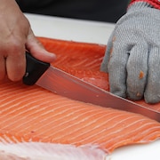 Un poissonnier tranche un morceau de saumon.