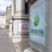 Une femme marche près d'un immeuble sur lequel on peut voir le logo de Sberbank.