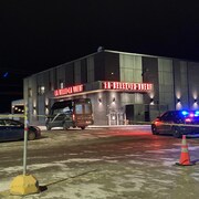 Des voitures de police sont à l'intérieur d'un périmètre autour d'un restaurant.