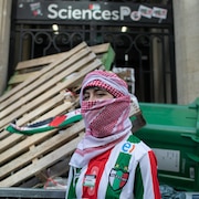 Une manifestante propalestinienne devant la porte de Sciences Po Paris bloquée par des palettes, des poubelles et des vélos, le 26 avril 2024.