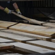 Un ouvrier manipule des planches dans une scierie.