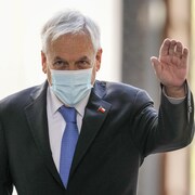 Sebastian Piñera, masqué, salue de la main gauche. 