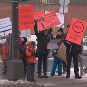 Des adultes et des enfants à un passage piéton en train de brandir des pancartes.