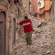 Un homme marche à travers les ruines.